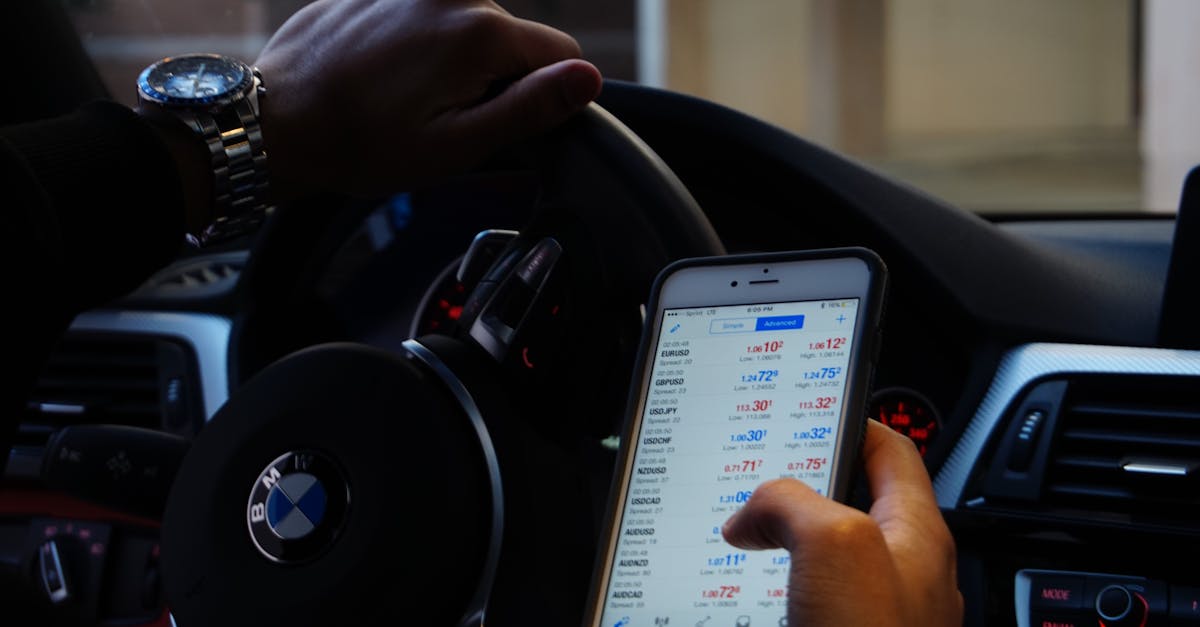 Person using mobile phone for currency trading while driving BMW car.